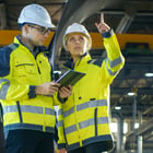 Image of a man and woman in safety coats and hardhats