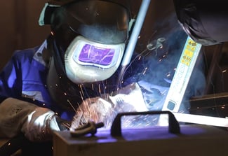 Mitarbeiter in er eigenen Hubtisch-Fertigung von COLUMBUS McKINNON schweißt gerade die Scherenkonstruktion eines Hubtischs.