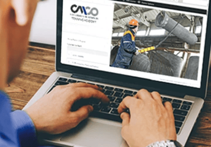Image of person looking at laptop with an overhead crane operator on screen